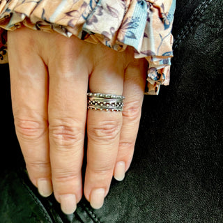 A set of 3 Karen Karch silver bands with repeating ball details on one side, both sides, and on the top stacked on a hand.