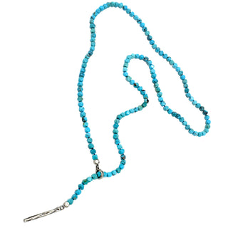 Turquoise beaded lariat necklace with a silver clasp on a white background