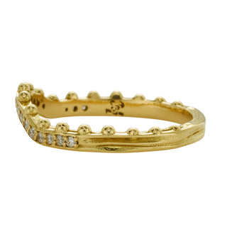 A curved, yellow gold band by Karen Karch with a row of ball details on one side, studded with colorless diamonds half way, side view.