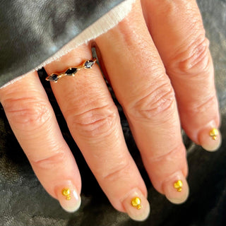 Karen Karch by Deme Wolfe 14k yellow gold black sapphire Mystical Marquise 3-stone stacking ring on a hand.