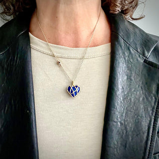 A Lapis Heart 18k Gold Charm with a Vine Cage wrapping the heart on a chain on a person