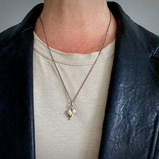 Karen Karch by Deme Wolfe Serpentine Love White Coral  Heart embraced by a Sterling Silver snake on chain on a person in a black leather jacket
