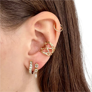A Karen Karch dangling diamond earrings with a line of three distinct shapes, each with a central diamond, set in gold claw settings on ear sttled with diamond Mainstay Cuff Hoop and Fishnet Ear Cuff