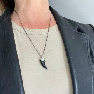 Karen Karch Draped Lucky Horn Amulet in Silver with Diamonds and Black Onyx on Chain on person in leather jacket