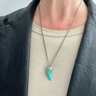 Karen Karch Draped Lucky Horn Amlet in Silver with Emeralds and Turquoise on chain on model in leather jacket