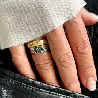 Karen Karch Glimmer domed Gold band on hand stacked with silver black diamond-studded signet wrap ring.