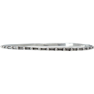 A Karen Karch silver bangle bracelet with a repeated ball detail along the edge, displayed on a white backround.