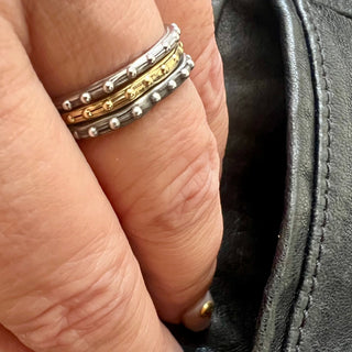 Karen Karch sterling silver and gold bands with a textured surface and ball embellishments along the circumference 3-ring stack on hand.