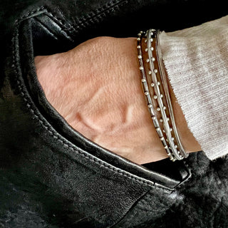 Set of 3 unique oval shape silver bangles by Karen Karch stacked on a wrist