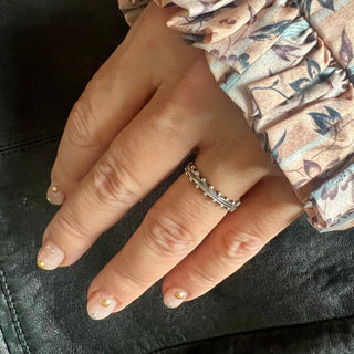 A Karen Karch sterling silver band ring with two rows of ball details on either side of a textured center on a hand.
