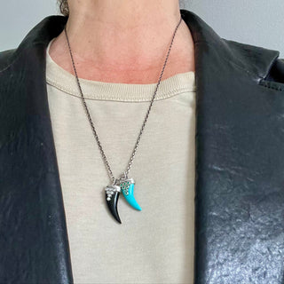 Karen Karch Draped Lucky Horn Amlet in Silver with Emeralds and Turquoise on chainlayered with Black Onyx and Diamonds on model in leather jacket