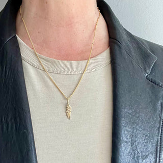 Karen Karch by Deme Wolfe 10k yellow gold Victory wing charm on chain on person in leather jacket
