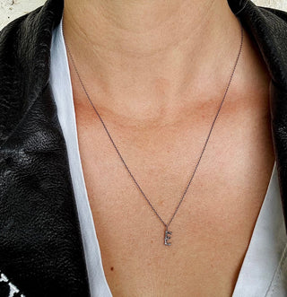 Karen Karch Textured Silver Mini Entwined Letter 'E' pendant on a chain on  a person.