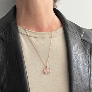 Karen Karch by Deme Wolfe Pink rose quartz pendant with gold frame with sharp claws on a chain on a person in leather jacket