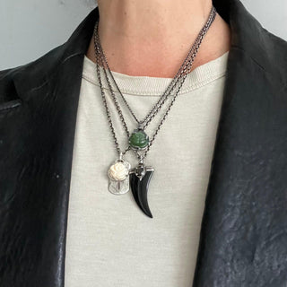 Karen Karch Layered Silver Amulets including Jade and White Coral Rosebud and Black Onyx Horn on a person