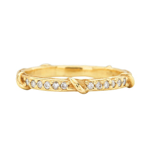 A weathered band in 18k yellow gold is detailed with organic twining vines is studded with colorless brilliant cut diamonds on the top half shown on a white background.