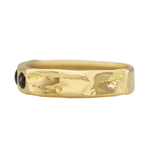 A Karen Karch 18k Gold unisex band with two rose-cut black diamonds of different sizes sunken into the surface, side view, on a white background.