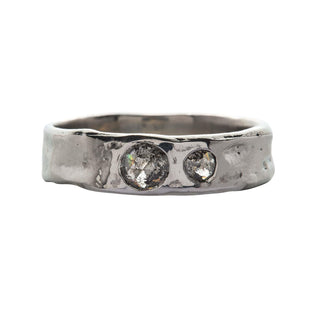 A Karen Karch Platinum unisex band ring with two rose-cut salt & pepper diamonds of different sizes sunken into the surface on a white background.