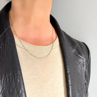 Karen Karch 1.8mm 14k yellow gold diamond-cut cable chain close up on a neck. 