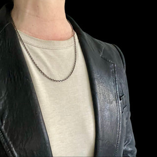 Karen Karch oxidized silver diamond-cut cable chain necklace with a lobster lock clasp and a branded end tag on a person