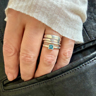 Karen Karch 925 sterling silver ALWAYS FOUR RING STACK of smooth irregular bands in different widths, one with a princess cut Aquamarine on a hand.