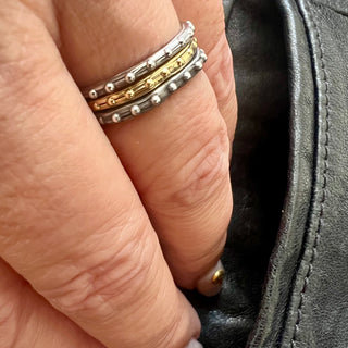 Karen Karch sterling silver and gold bands with a textured surface and ball embellishments along the circumference 3-ring stack on hand. 