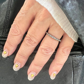 A Karen Karch sterling silver band  with a textured surface and ball embellishments along the circumference on a hand.