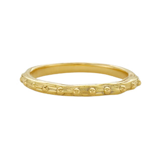 A Karen Karch 18k yellow gold band  with a textured surface and ball embellishments along the circumference on a white background.