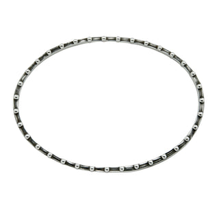 Top View of a  Karen Karch oval-shaped silver bangle bracelet with a weathered texture and repeating ball details on each side on white background.
