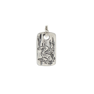 A silver rectangular weathered dog tag engraved with a dragon on a textured bail with a crossing vine detail on a white background.