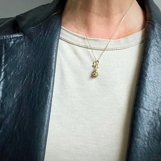 Karen Karch Reminiscent Rose yellow gold rosebud charm with a twining vine that forms a loop ending in a ruby on a chain  on a person