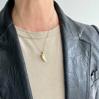 Karen Karch 18k Yellow Gold Diamond Dotted Lucky Horn White Coral  on Chain on person in leather jacket