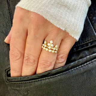 Karen Karch 18k Yellow Gold bezel set Colorless Diamond Ring configured in the shape of a tiara for the finger stacked with a 6 diamond Grace Band on a hand.