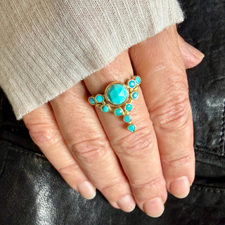 Close up of a hand wearing a custom 18k yellow gold Floating Star Turquoise cocktail ring.