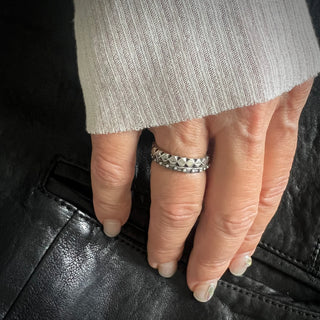 Karen Karch Outshine Weathered 3mm silver band with a textured, angular repeating pattern design stacked with Jaipur Evermore on a hand.