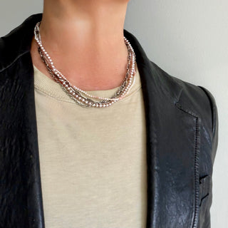 Four distinct strands—pink freshwater pearls, delicate shaded pink opal beads, with two unique silver chains - create a chic tangled necklace united with a substantial weathered toggle closure on a neck. 