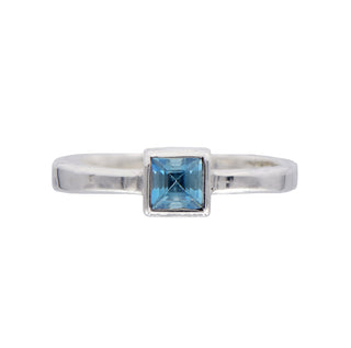 Karen Karch Silver ring with an Aquamarine Princess Cut Square gemstone on an irregular polished band side view on white background.