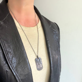 Karen Karch blackened silver dog tag pendant on a 25" silver chain on a person.