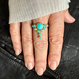 Close up of a hand wearing a custom 18k yellow gold Floating Star Turquoise cocktail ring.