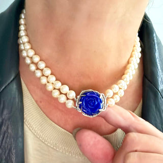 Karen Karch custom carved lapis rose centerpiece clasp on double strand of pearls, close up on a person's neck.