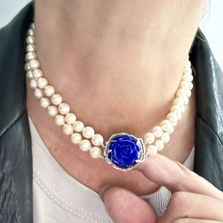 Karen Karch custom carved lapis rose centerpiece clasp on double strand of pearls, close up on a person's neck.