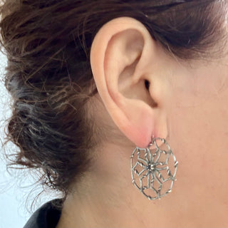 Close-up of a person wearing a unique  Karen Karch Silver Desert Flower Hoop Earring.