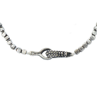 Karen Karch Lithe signature gray diamond-studded medium silver hook clasp close up on irregular silver beads on white background.