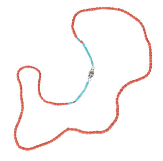 A Karen Karch beaded necklace featuring barrel shape red coral beads with a central section of turquoise tube beads and a silver logo tag, displayed on a clean white background.