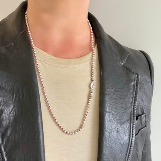 Karen Karch Epitome 3mm Pink Freshwater Pearl Necklace shown on a person with a t-shirt and leather jacket. 