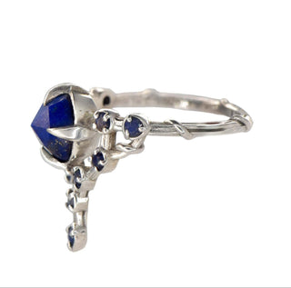 A Karen Karch silver cocktail ring featuring a large round lapis center stone surrounded by smaller lapis stones, in a star-like formation, side view.