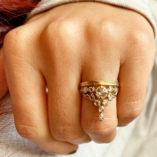 A Karen Karch 18k Yellow Gold ring featuring a round rose cut colorless diamond center stone surrounded by smaller colorless diamonds, in a star-like formation on a hand