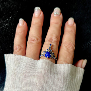 A Karen Karch silver cocktail ring featuring a large round lapis center stone surrounded by smaller lapis stones, in a star-like formation on a hand.
