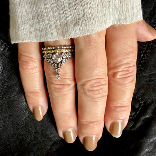 A Karen Karch Oxidized Sterling Silver  ring featuring a round rose cut white sapphire center stone surrounded by smaller white sapphires, in a star-like formation stacked on a hand.
