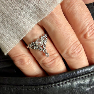 A Karen Karch Oxidized Sterling Silver  ring featuring a round rose cut white sapphire center stone surrounded by smaller white sapphires, in a star-like formation on a hand.